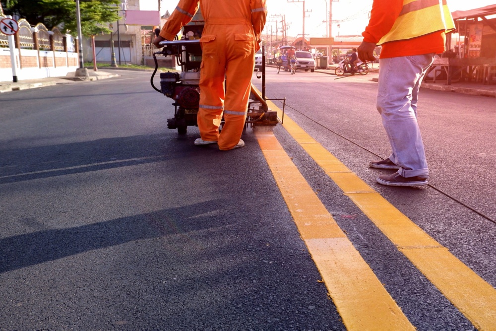 two road workers painting the road